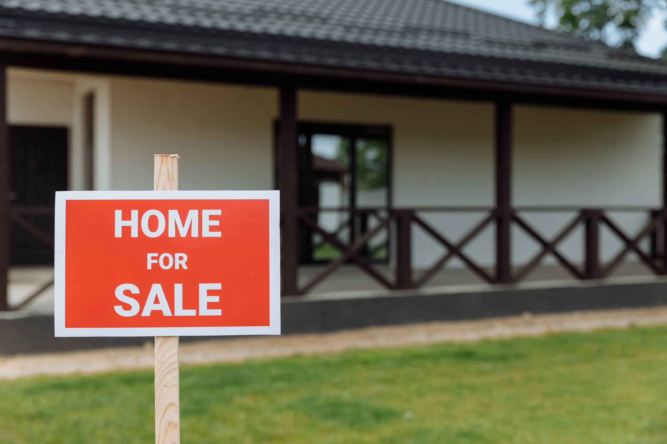 A 'Home For Sale' yard sign in front of a house