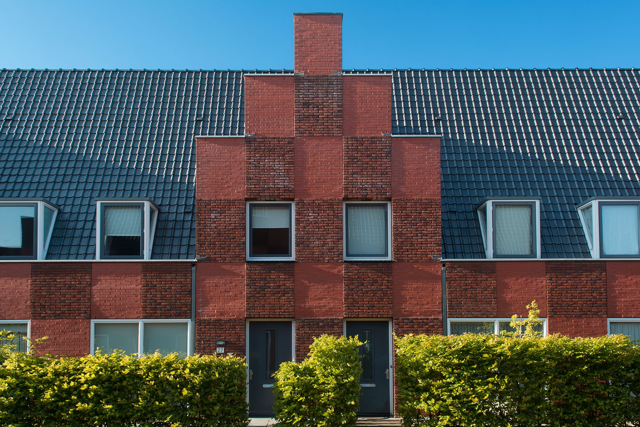 A red-brick suburban house exterior under a blue sky